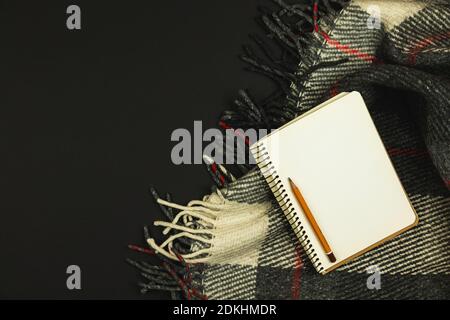 Arbeitsplatzgestaltung mit Decke und Notizbuch, schwarzer Hintergrund, Minimalismus, Kopierfläche, Draufsicht Foto Stockfoto