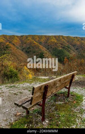 Eine Bank mit Blick auf die Berge und Herbstfarben im malerischen Dorf Dilofo auf Tymfi Berg, Zagori, Epirus, Griechenland Stockfoto