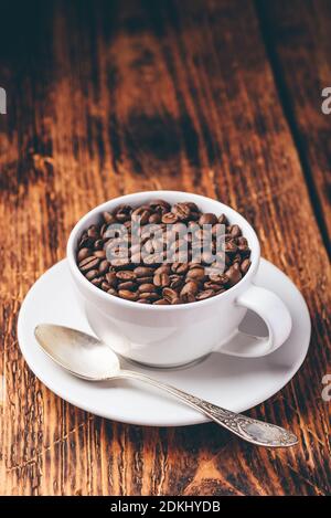 Geröstete Kaffeebohnen im Cup über Holz- Oberfläche Stockfoto