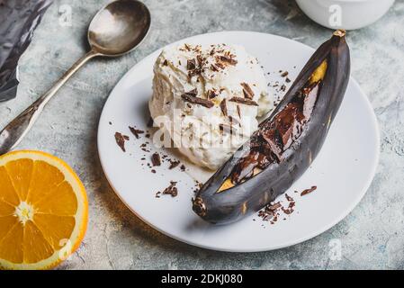 Süßes Dessert. Gegrillte Banane mit dunkler Schokolade, Zitronensaft und Vanilleeis. Stockfoto