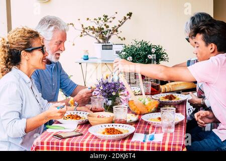 Familienmittagspause zusammen mit kaukasischen Gruppen gemischter Altersklassen Die Menschen genießen Zeit und essen am Tisch - Menschen Viel Spaß mit Essen Freizeitbeschäftigung - fröhliche Männer und Frauen verschiedenen Alters und Jahren alt Stockfoto