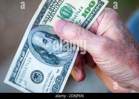 Hundert Dollar-Schein in der Hand des älteren Mannes, Nahaufnahme Stockfoto