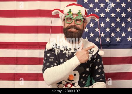 Hey look. Happy hipster Punkt Zeigefinger auf etwas. Bärtiger Mann zeigen und Lachen. Amerikanische Flagge im Hintergrund. Punkt Geste. Werbung zeigen. Frohe Weihnachten. Frohes neues Jahr. Stockfoto