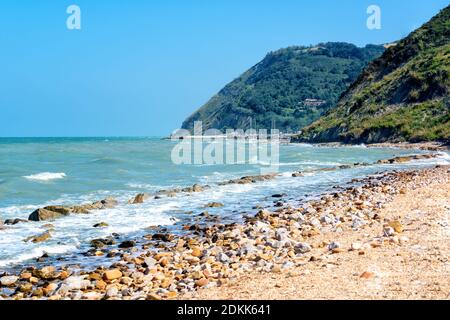 Schöne Meereslandschaft mit Blick auf Meer und Berge am Sommertag, Küste mit Kieselsteinen und cutwater. Adriaküste, Rimini, Italien Stockfoto