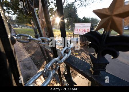 Austin, TX USA 15. Dezember 2020: Schild mit der Aufschrift 'Capitol Building and Grounds CLOSED to all Visitors' sitzt hinter den verschlossenen Toren des Texas Capitol in Austin am Abend bevor der Gouverneur von Texas, Greg Abbott, die Wiedereröffnung des Geländes für die Öffentlichkeit anordnete. Das Capitol ist seit Monaten geschlossen, nachdem Vandalismus auf dem Gelände und Gebäude während der Proteste gegen Polizeigewalt nach dem Mord an George Floyd im Mai 2020. Kredit: Bob Daemmrich/Alamy Live Nachrichten Stockfoto
