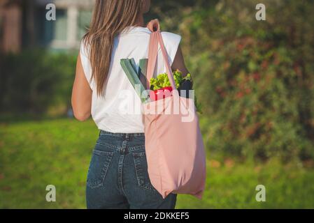 Junge Frau mit rosa Öko wiederverwendbare Textil Lebensmittelbeutel mit Frisches Bio-Gemüse Stockfoto