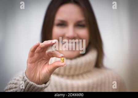 Junge glückliche Frau hält Fischöl Pille oder Vitamin D Ergänzung. Stockfoto