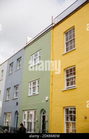 Reihe von bunten britischen Häusern mit Handläufen und Pflanzen Stockfoto