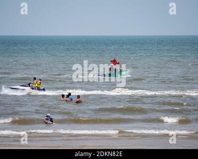 Bai Sau oder Zurück Strand in Vung Tau in der Provinz Bang Ria-Vung Tau in Südvietnam, mit Touristen, einem Wasserfahrzeug und einem runden Fischerboot, typisch für Stockfoto