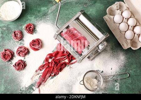 Nudelmaschine mit Teig auf farbigem Hintergrund Stockfoto