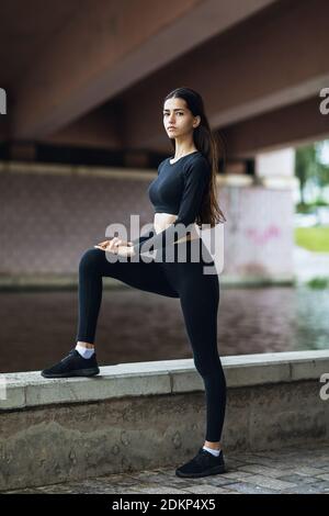 Eine schöne Brünette in Sportswear führt Übungen am Wasser. Stockfoto