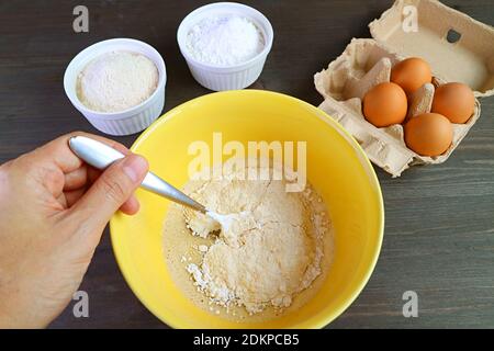 Man's Hand Mischen Zutaten in einer Schüssel zum Backen ganze Weizenmuffins Stockfoto