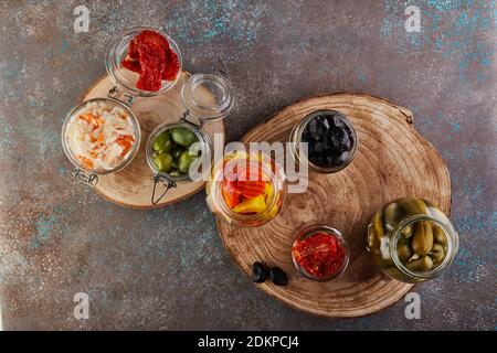 Fermentierte Dosen vegetarische Lebensmittel Konzept. Sauerkraut, eingelegte Karotten, eingelegte Gurken, eingelegte Oliven und Oliven, getrocknete Tomaten in Gläsern. Der Stockfoto