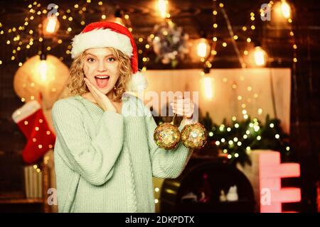 Dekoratives Zubehör Shop. Girl santa hut halten Sie die goldenen Kugeln Dekorationen für den Weihnachtsbaum. Ihre Weihnachtsdekoration prüfen und ersetzen Sie etwas abgenutzt ist. Vorbereitung Dekorationen im Voraus. Stockfoto