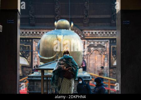 Kathmandu, Nepal. Dezember 2020. Eine nepalesische Hindu-Frau, die eine Gesichtsmaske trägt, bietet Lord Shiva rituelle Gebete im Pashupatinath-Tempel an.der Pashupatinath-Tempel hat sich den Anhängern durch die Annahme von Gesundheitsprotokollen wieder geöffnet. Wegen des Coronavirus wurden seit dem 20. März 2020 Tempel für Anhänger geschlossen. Pashupatinath ist einer der vier wichtigsten und berühmtesten hinduistischen religiösen Tempel in Asien für Anhänger von Shiva. Kredit: SOPA Images Limited/Alamy Live Nachrichten Stockfoto