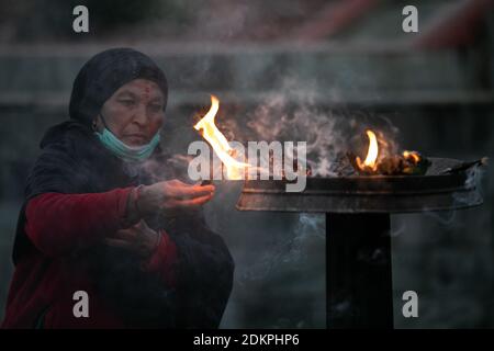 Kathmandu, Nepal. Dezember 2020. Eine nepalesische Hindu-Frau, die eine Gesichtsmaske trägt, bietet Lord Shiva rituelle Gebete im Pashupatinath-Tempel an.der Pashupatinath-Tempel hat sich den Anhängern durch die Annahme von Gesundheitsprotokollen wieder geöffnet. Wegen des Coronavirus wurden seit dem 20. März 2020 Tempel für Anhänger geschlossen. Pashupatinath ist einer der vier wichtigsten und berühmtesten hinduistischen religiösen Tempel in Asien für Anhänger von Shiva. Kredit: SOPA Images Limited/Alamy Live Nachrichten Stockfoto