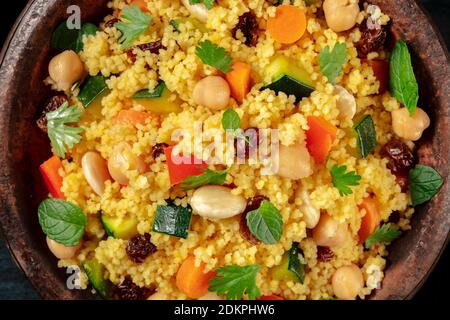 Couscous mit Gemüse, Mandeln, Rosinen und Kräutern, Nahaufnahme über dem Kopf in einer Tagine Stockfoto