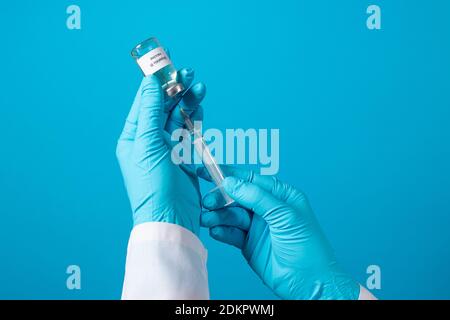 Ein Arzt oder Labortechniker hält ein Fläschchen mit einem Hepatitis-B-Impfstoff in der Hand. Mit einem Platz für Text auf blauem Hintergrund. Stockfoto