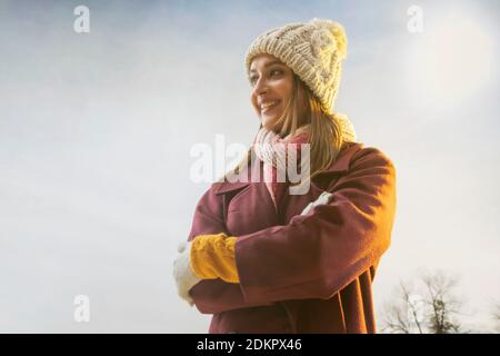 PORTRÄT EINER JUNGEN FRAU IN WINTERKLEIDUNG WEGSCHAUEN GLÜCKLICH Stockfoto