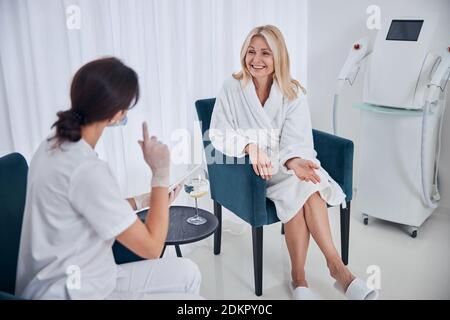 Glücklich lächelnde Geschäftsfrau, die mit Kosmetologe in Beauty-Center Stockfoto
