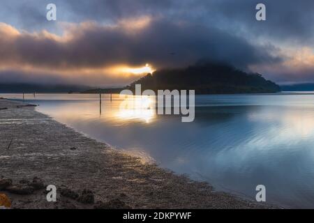 Ein nebliger Start in den Tag mit Wolken über dem Fluss und Inseln in Mooney Mooney am Hawkesbury River, Central Coast, NSW, Australien Stockfoto