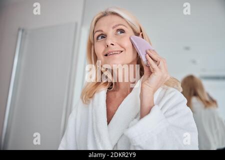 Happy fröhlich blonde Dame genießen tolle Zeit mit Silikon-Basis Bürste im Badezimmer Stockfoto