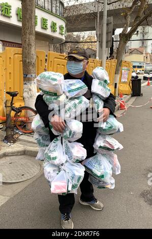 (201216) -- PEKING, 16. Dezember 2020 (Xinhua) -- Feng Feng, ein netzgestützter Gemeindearbeiter, trägt Medikamentenpakete für Bewohner des Jiang'an Bezirks Wuhan, der Hauptstadt der zentralchinesischen Provinz Hubei, 24. Februar 2020. Wenn man auf 2020 zurückblickt, gibt es immer ein paar warme Bilder und berührende Momente: Das Engagement an vorderster Front im Kampf gegen die Epidemie, die Beharrlichkeit auf dem Weg aus der Armut, der Mut, die Verantwortung auf dem Damm gegen die Flut zu übernehmen, die Freude und der Stolz beim Erreichen des Gipfels des Berges Qomolangma... Diese Menschen und Dinge berühren unsere Herzen und geben Stockfoto