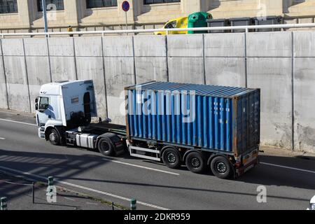 Weißer LKW mit blauem Container in einer zweispurigen Fahrbahn. Stockfoto