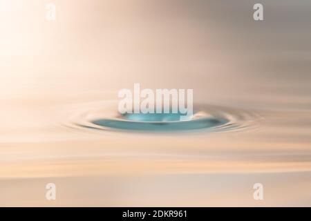 Nahaufnahme eines Wassertropfens, der auf die Wasseroberfläche trifft und einen Hohlraum erzeugt. Dieses Foto kann für alle Arten von Zwecken verwendet werden. Stockfoto