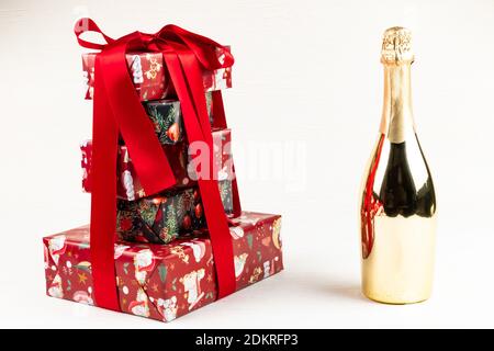 Festliche Neujahr Boxen mit einem roten Satinband gebunden Mit Geschenken auf einem weißen Holztisch neben gestapelt Eine Flasche Champagner Stockfoto