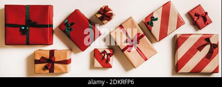 Flache festliche Geschenkschachteln aus Geschenkpapier, verziert mit grünen und roten Schleifen auf weißem Hintergrund, Draufsicht, horizontale Komposition. Weihnachten Boxtag Konzept Stockfoto