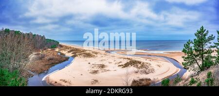 Weißer Sandstrand und Ostsee umgeben von Nadelbäumen Wald in der Ostsee. Die Weiße Düne und die Ostsee sehen in Saulkrasti im Frühjahr, Lettland. Stockfoto