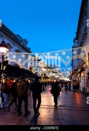 Belgrad, Serbien - 10. Dezember 2020: Knez Mihailova Straße in Belgrad. Peapple Spaziergang am Abend durch die Straße geschmückt für Weihnachten und Stockfoto