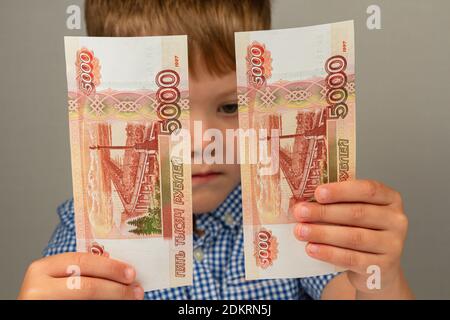 Das Kind erhielt Geld vom Staat während des Coronavirus Und hält sie in seinen Händen Stockfoto