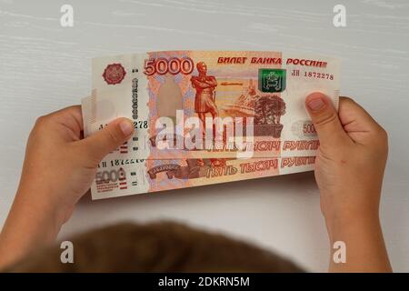 Das Kind erhielt Geld vom Staat während des Coronavirus Und hält sie in seinen Händen Stockfoto