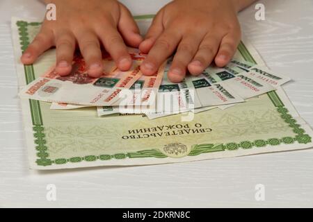 Das Kind erhielt Geld vom Staat während des Coronavirus Periode Inschrift Geburtsurkunde Stockfoto