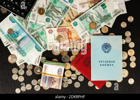 Beschäftigungsgeschichte und Militärausweis und Münzen mit Banknoten liegen Auf einem schwarzen Holztisch Inschrift Beschäftigung Geschichte russische Föderation Stockfoto