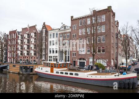 Amsterdam, Niederlande - 25. Februar 2017: Alte traditionelle Wohnhäuser und Hausboote entlang der Kanalküste in der Amsterdamer Altstadt Stockfoto