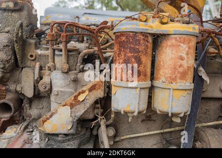 Eine Nahaufnahme eines alten und verrosteten Dieselmotors mit Flecken von gelber Farbe, orangefarbenem Rost und braunem Schlamm Stockfoto