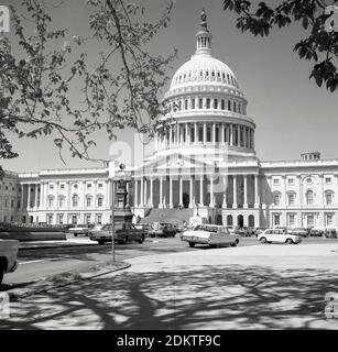 Historische Autos aus der Zeit der 1960er Jahre parkten auf einer Straße am Capitol Hill vor dem Capitol Building der Vereinigten Staaten in Washington DC, USA. Im neoklassizistischen Stil erbaut, mit einer Kuppel und großen Säulen, ist es Sitz des US-Kongresses, der Legislativabteilung der Bundesregierung und beherbergt die Kammern des Oberkörpers, des Senats und des Unterkörpers, des Repräsentantenhauses, die beiden Organe, die den Legislativzweig der amerikanischen Regierung bilden. Stockfoto