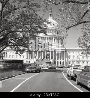 Historische Autos aus der Zeit der 1960er Jahre parkten auf einer Straße am Capitol Hill vor dem Capitol Building der Vereinigten Staaten in Washington DC, USA. Im neoklassizistischen Stil erbaut, mit einer Kuppel und großen Säulen, ist es Sitz des US-Kongresses, der Legislativabteilung der Bundesregierung und beherbergt die Kammern des Oberkörpers, des Senats und des Unterkörpers, des Repräsentantenhauses, die beiden Organe, die den Legislativzweig der amerikanischen Regierung bilden. Stockfoto