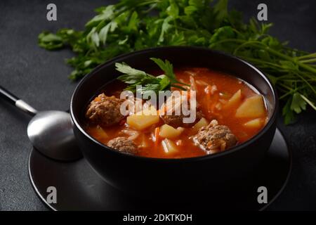 Patatesli Sulu Kofte - Turkish soup with meatballs in black bowl Stock Photo