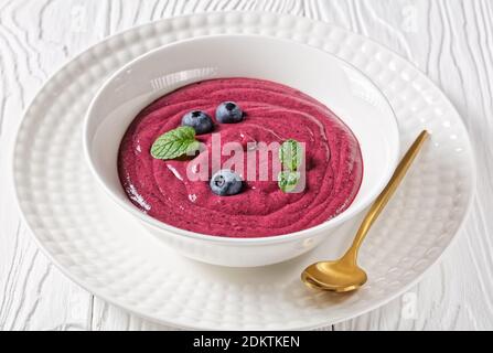 Blueberry and banana smoothie bowl with yogurt, cashew, chia seeds, and flax seeds on a white wooden background with ingredients, top view, close-up Stock Photo