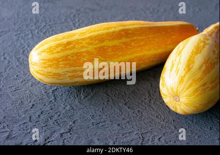 Gelbe Zucchini auf grauem Hintergrund in den Farben des Jahres 2021 - leuchtend gelb und ultimativ grau. Stockfoto