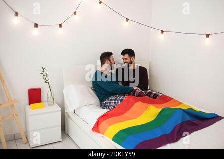 Gay Männer Paar mit zarten Momente sitzen auf dem Bett zu Hause - homosexuell, Liebe und Beziehung Konzept - Schwerpunkt auf rechten Kerl Gesicht Stockfoto