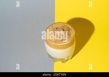 Dalgona Kaffee mit üppigem Schaum bestreut mit Schokolade auf einem gelben und grauen Hintergrund. Trendiges Koreanisches Getränk Stockfoto