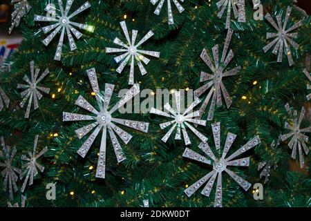 Schneebedeckte Kunsttanne mit Hightech-Weihnachtsschmuck in Form von Sternen. Stockfoto