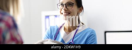 Lächelnder Tierarzt hält Katze in den Armen und kommuniziert mit dem Besitzer. Stockfoto