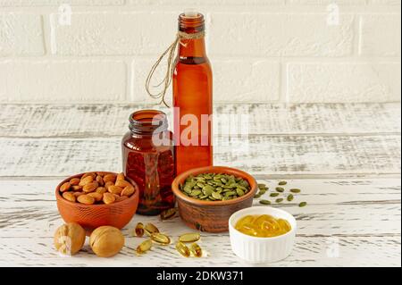 Formen von Omega-oder Fischöl Supplemets - Gel-Kapseln. Flüssiges Öl und Nüsse auf Holztisch. Gesunde Ernährung Stockfoto