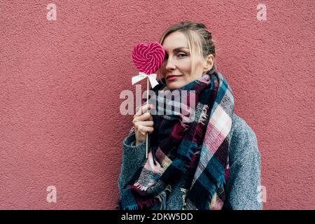 Charmante Frau mit großen herzförmigen Karamell rosa Lollipop. Stockfoto